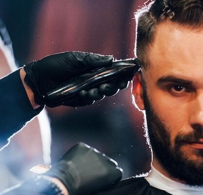 Vista de cerca de un joven barbudo que se sienta y se corta el cabello en la barbería _ Foto Premium